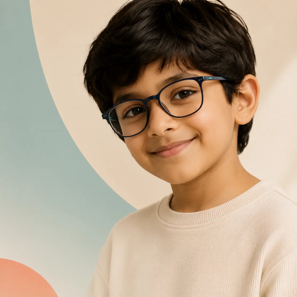 A young boy with dark hair wearing black cat-eye eyeglasses and a cream-colored ribbed sweater, set against a soft beige background with abstract pastel shapes. Smiling child wearing stylish blue eyeglasses | Glasseo Eyewear